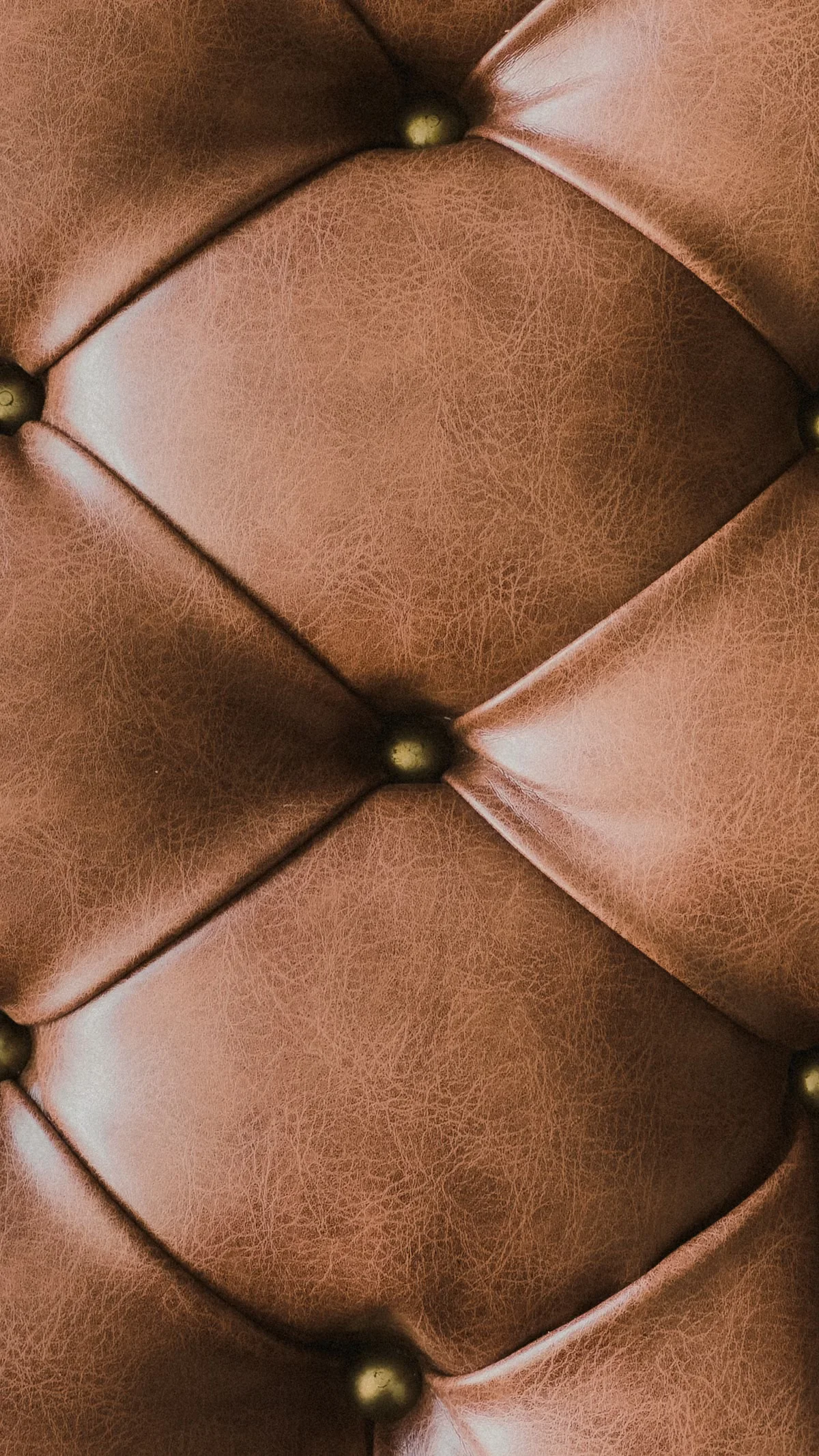 Close-up of tan leather upholstery with diamond quilting and brass nail-head studs — hardware integrity, finish consistency and stitch quality are among the primary checkpoints in an AQL leather goods inspection