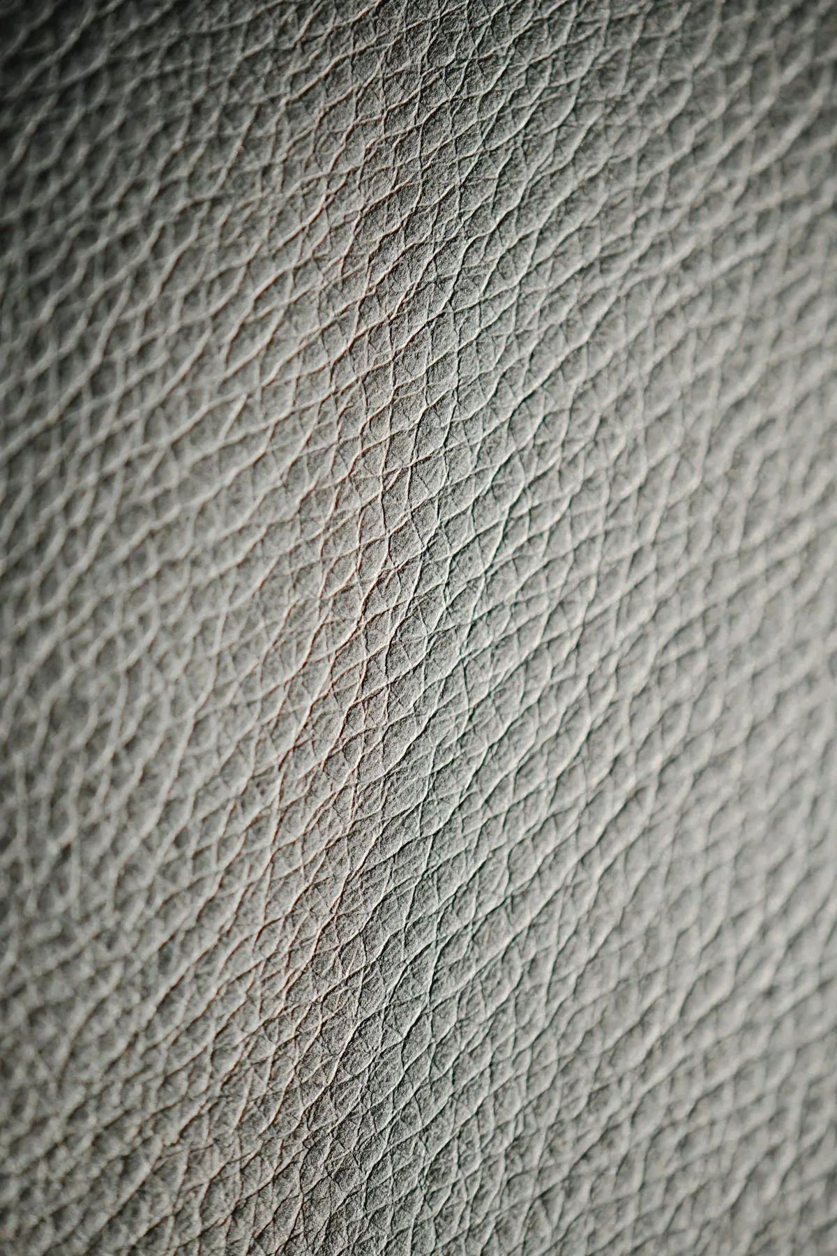 Macro close-up of top-grain leather surface showing uniform pebbled grain pattern — characteristic of the corrected and finished leather grade widely used in mid-range wholesale handbags