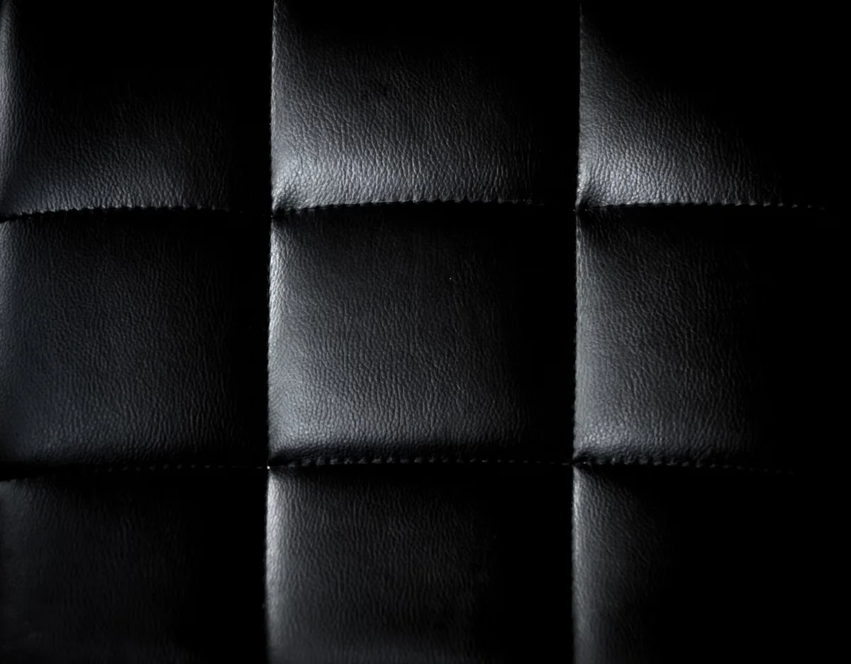 Black leather panels with raised quilted stitching detail — illustrating the tactile surface quality and craftsmanship expression that suede and specialty textures bring to wholesale leather bag production